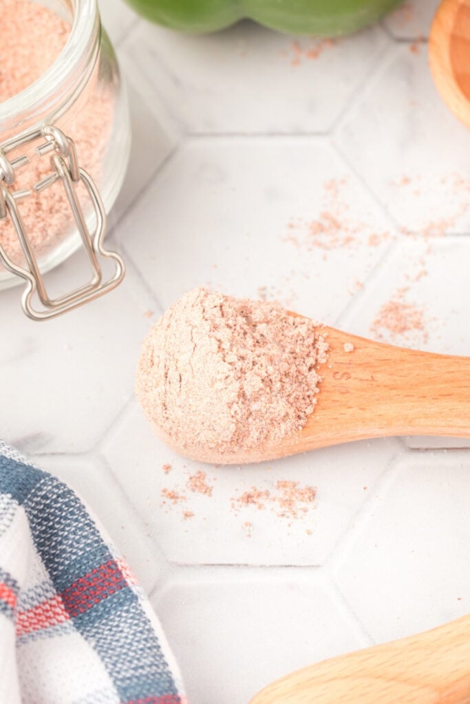 Wooden spoon filled with Homemade Fajita Seasoning beside a glass jar