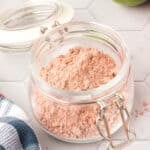 Square image of Homemade Fajita Seasoning in a glass jar on a white tile surface