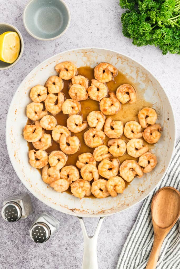 Cooked Hibachi Shrimp coated in garlic butter sauce in a white skillet.