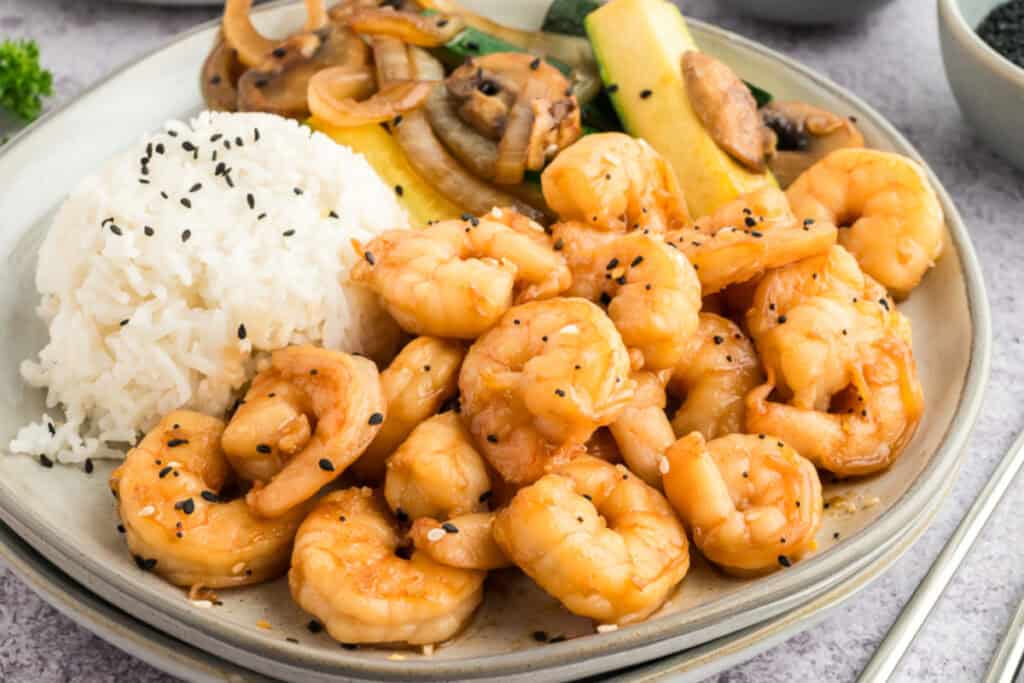 Close-up of Hibachi Shrimp served with white rice, zucchini, mushrooms, and onions, garnished with sesame seeds.