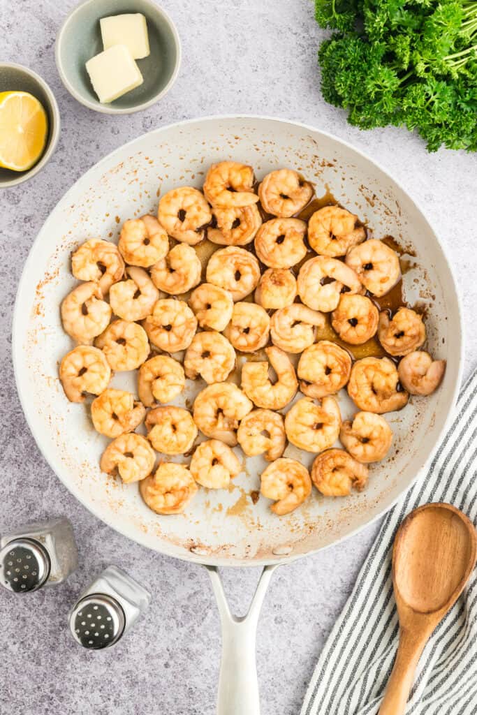 Hibachi Shrimp cooking in a white skillet with sauce.