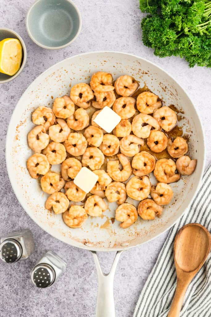 Butter added to cooked Hibachi Shrimp in a skillet.