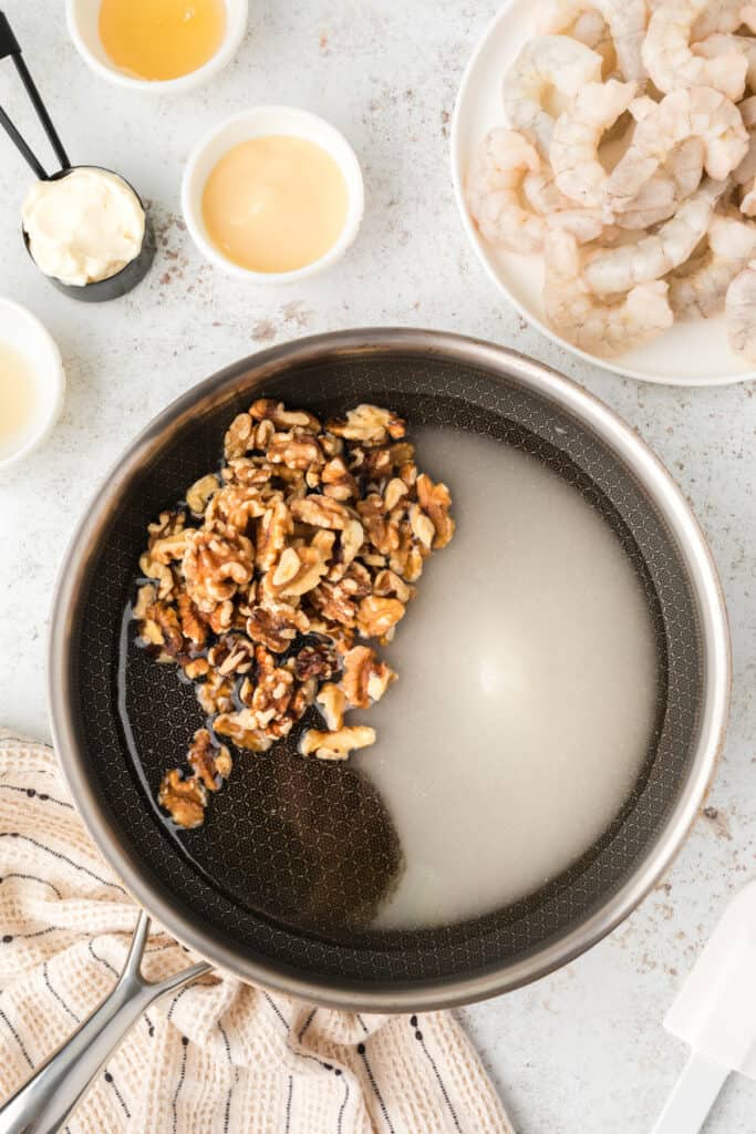 Walnuts, sugar, and honey cooking in a skillet for homemade Honey Walnut Shrimp