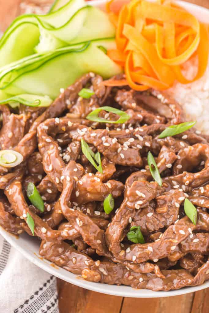Close-up of Korean Beef Bulgogi with sesame seeds and green onions served with rice and vegetables