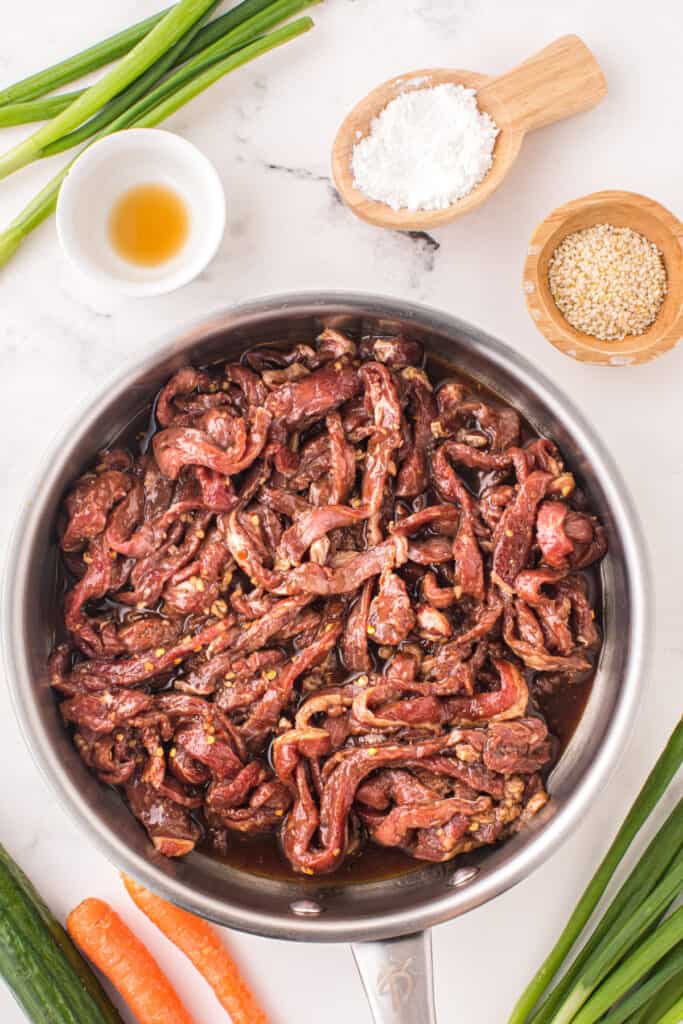 Marinated Korean Beef Bulgogi beef strips in a skillet before cooking with bulgogi sauce