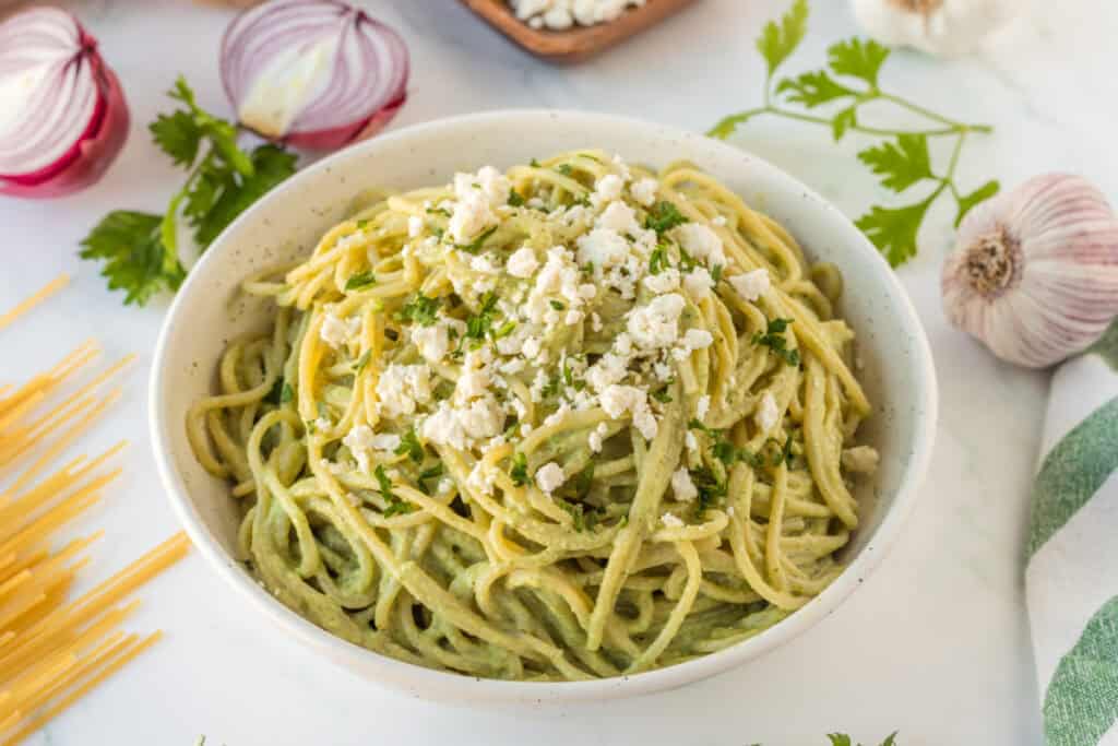 Creamy Espagueti Verde garnished with queso fresco in serving bowl