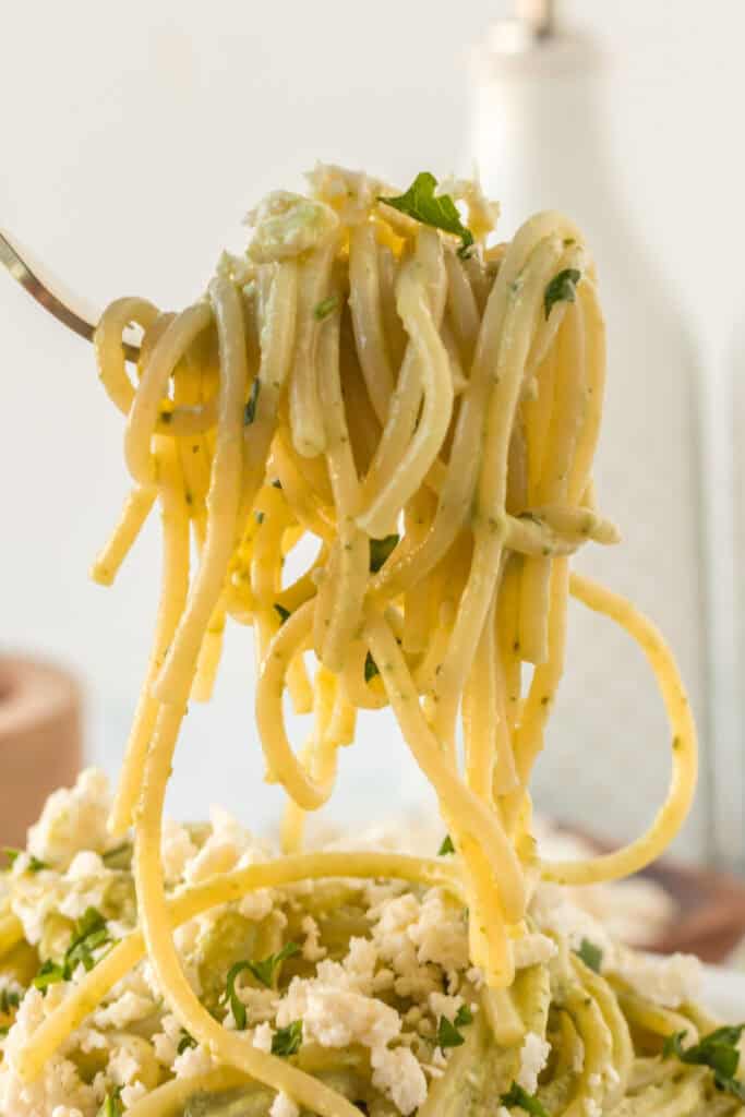 Fork twirling creamy Mexican Green Spaghetti with poblano sauce and queso fresco