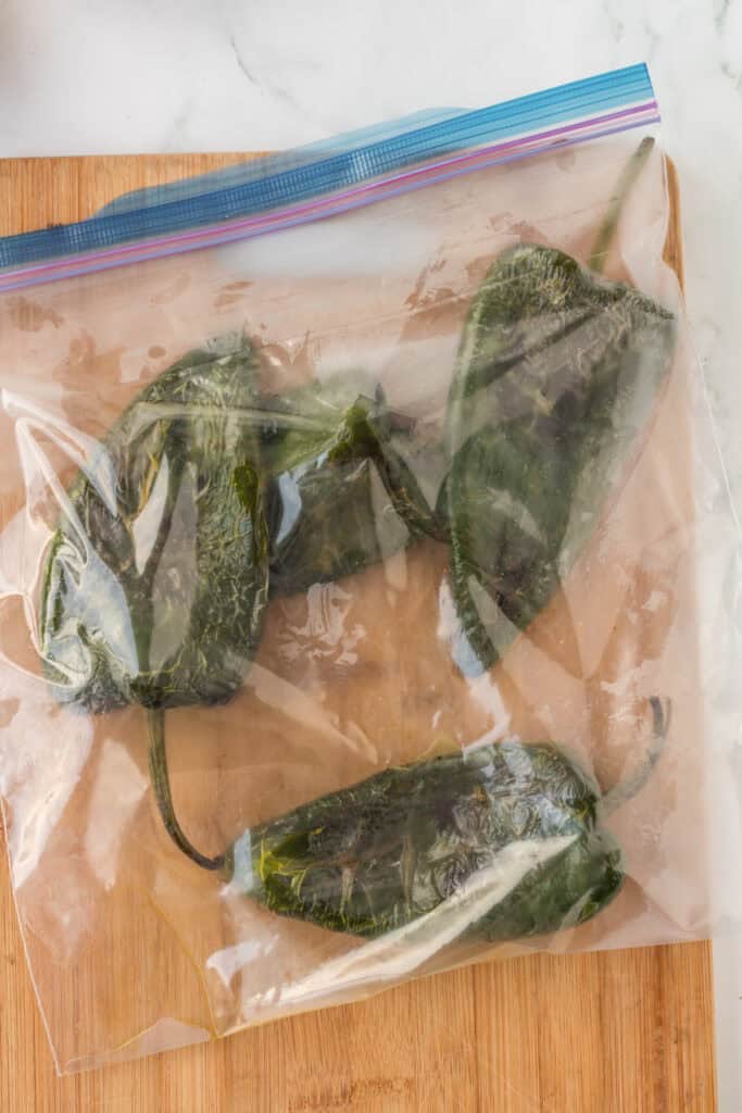 Roasted poblano peppers steaming in zip-top bag for Mexican Green Spaghetti