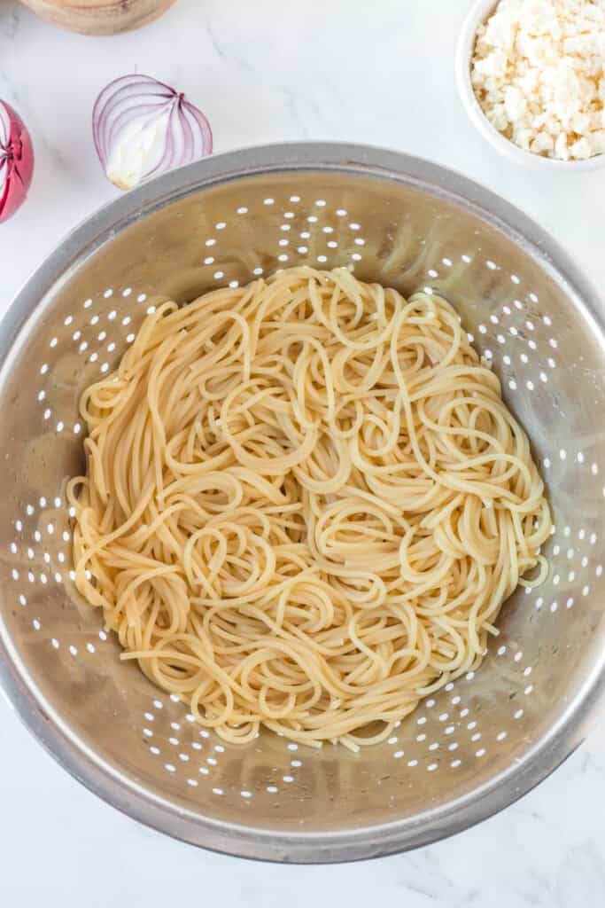 Cooked spaghetti drained in colander for creamy poblano pasta recipe
