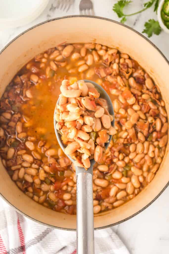 Spoonful of Ranchero Beans with bacon, tomatoes, and jalapeño over a Dutch oven