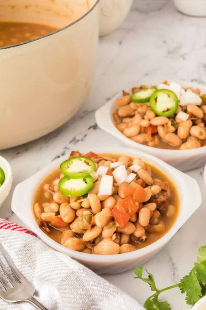 Bowls of Ranchero Beans topped with jalapeño slices and chopped onion