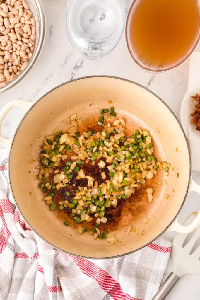 Pinto beans, bacon, tomatoes, broth, and spices added to a Dutch oven for Ranchero Beans