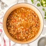 Ranchero Beans recipe in a Dutch oven with bacon, tomatoes, and pinto beans
