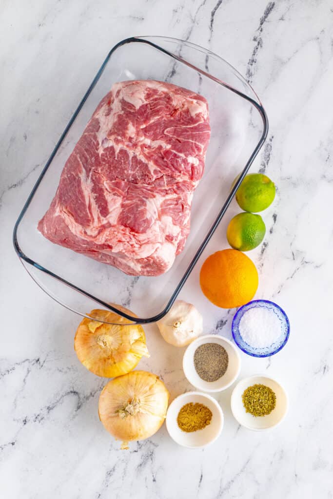 Slow Cooker Carnitas ingredients with pork shoulder, onions, garlic, orange, lime, and seasonings
