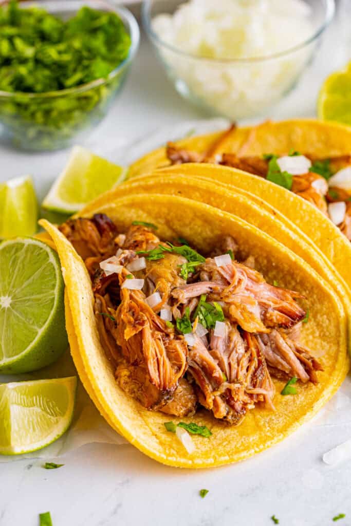 Close up of Slow Cooker Carnitas taco with onion, cilantro, and lime
