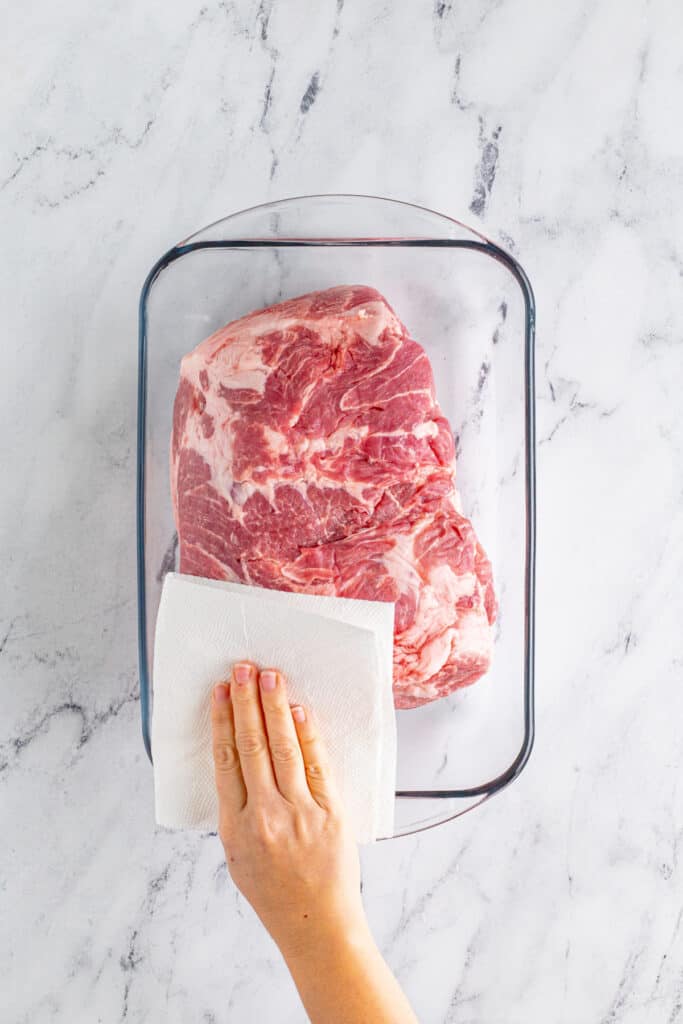 Patting dry pork shoulder for Slow Cooker Carnitas recipe