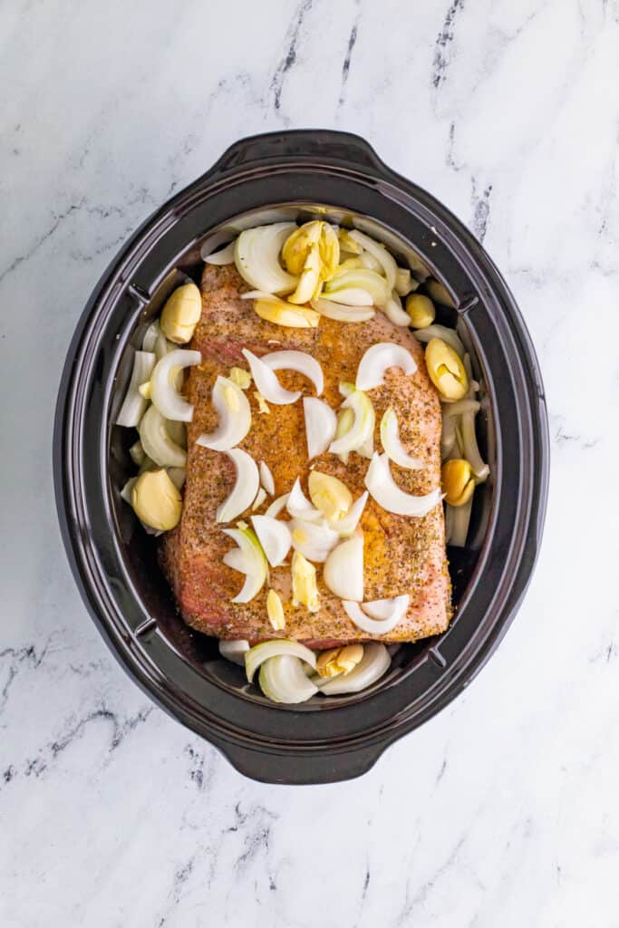 Slow Cooker Carnitas with onions and garlic added to crockpot