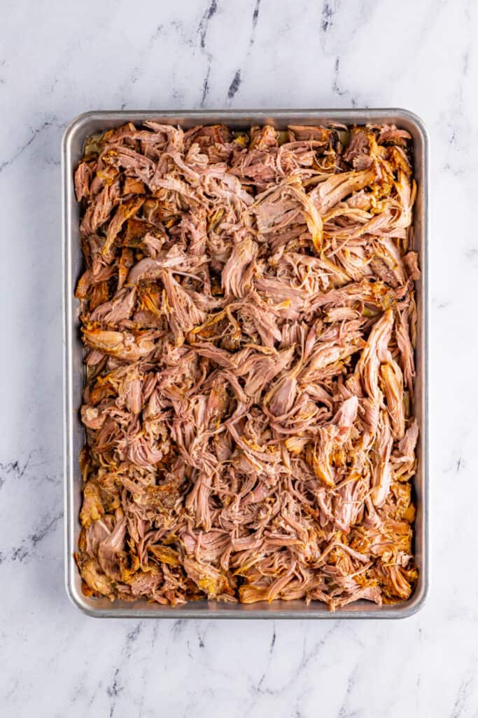 Shredded Slow Cooker Carnitas spread on baking sheet before broiling