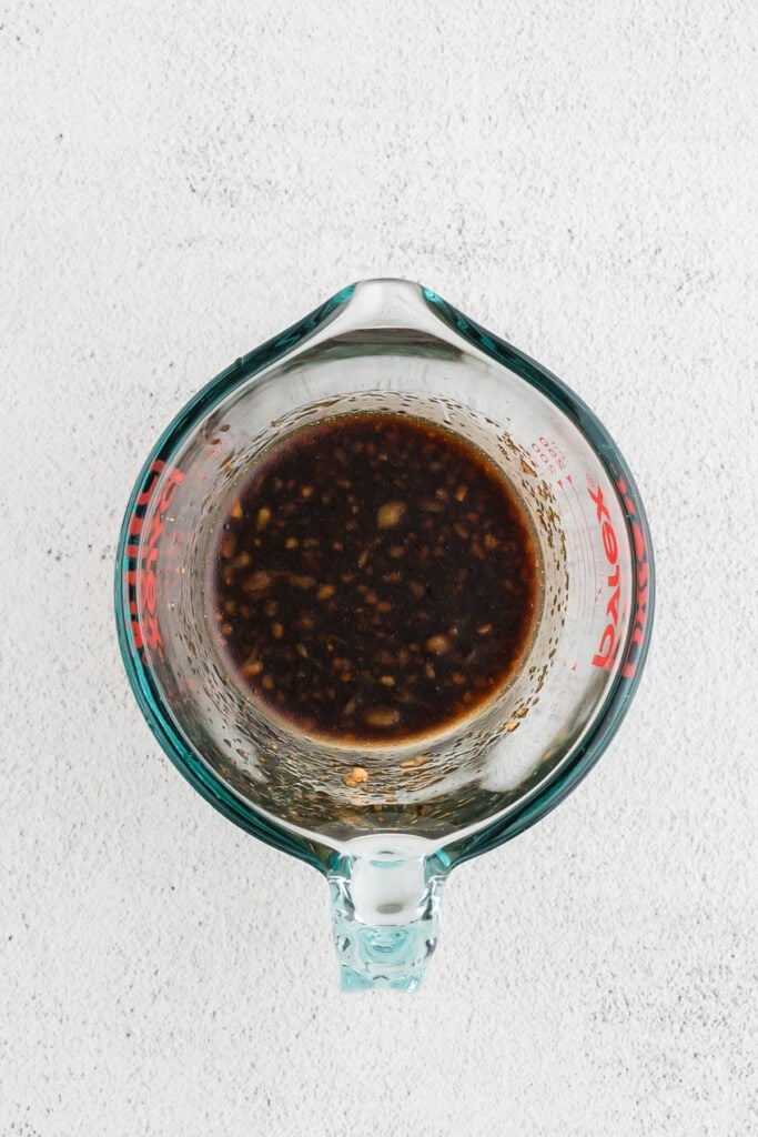 Close-up of homemade hibachi chicken sauce made with soy sauce, garlic, ginger, sesame oil, and brown sugar in a glass measuring cup.