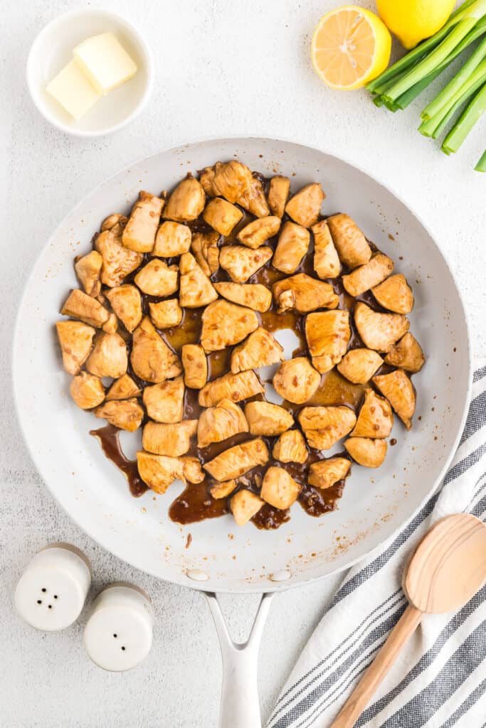 Hibachi Chicken simmering in a buttery soy garlic sauce in a skillet with fried rice served nearby.