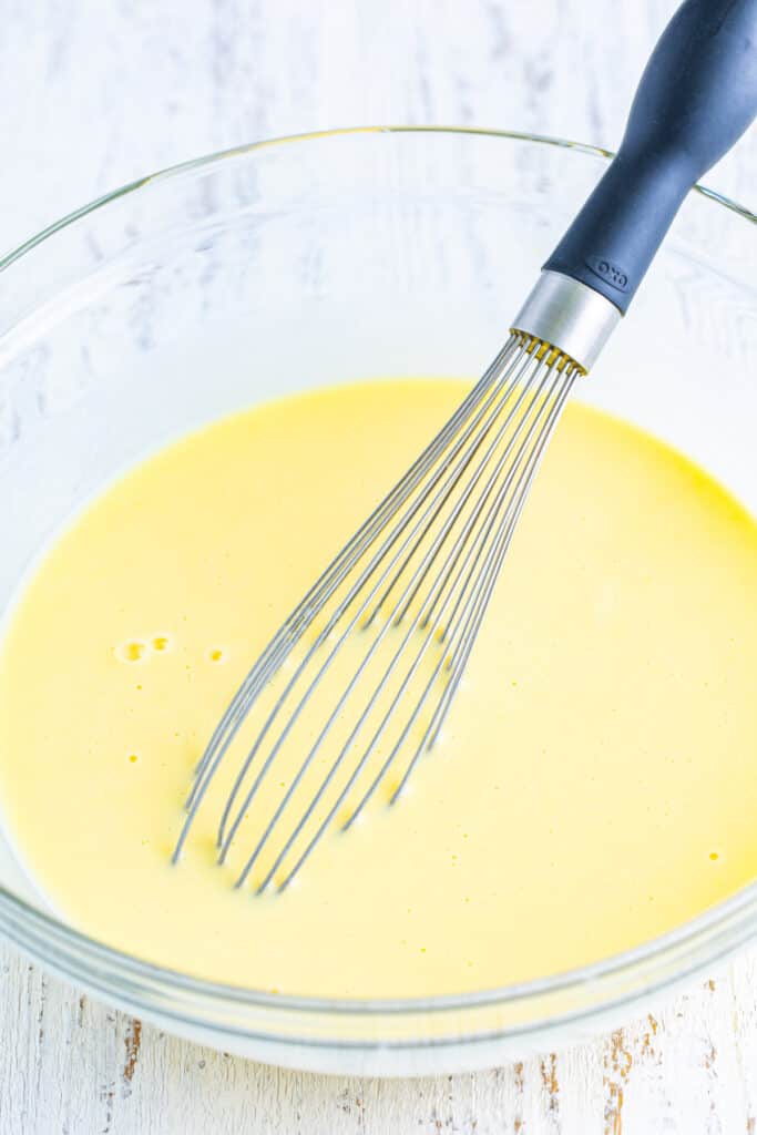 Vanilla pudding mixture being whisked in a clear glass bowl for Banana Split Trifle.