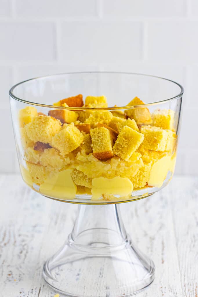 Additional layer of cubed yellow cake added to the trifle bowl over pineapple and pudding for Banana Split Trifle.