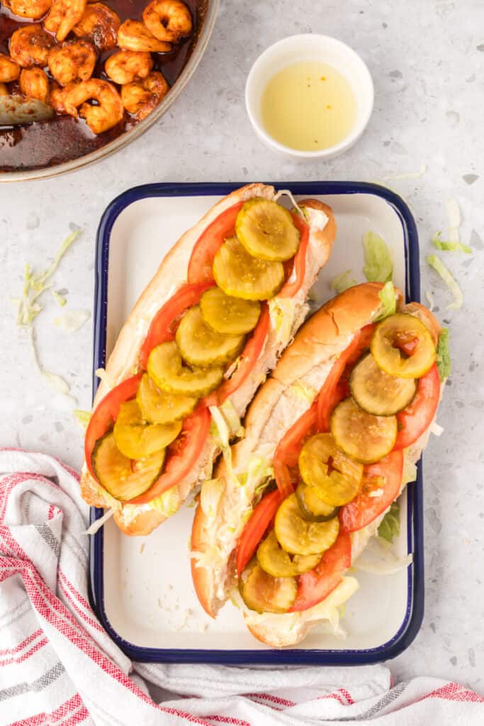Pickle slices added to shrimp po'boy sandwiches