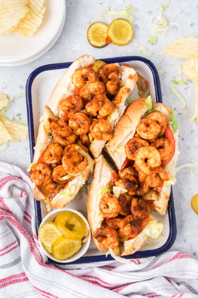 Close-up of a shrimp po'boy sandwich with lettuce, tomatoes, and pickles