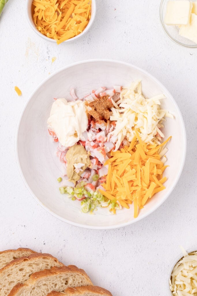 Imitation crab, shredded cheese, mayonnaise, mustard, green onions, and seasoning in a mixing bowl before being combined