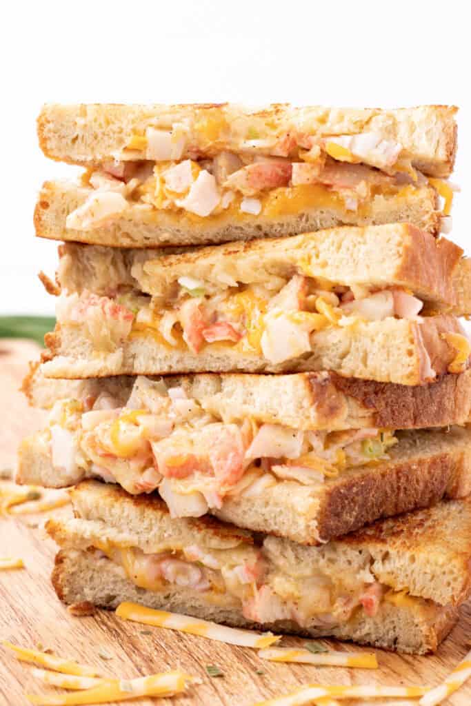 Close-up of stacked Cheesy Crab Melt sandwich halves showing the cheesy crab filling