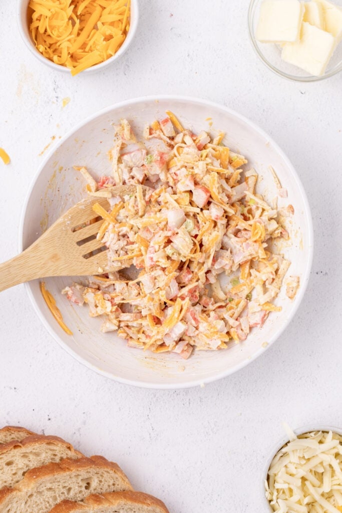 Cheesy crab filling mixed together in a bowl with shredded cheese, imitation crab, mayonnaise, and seasonings