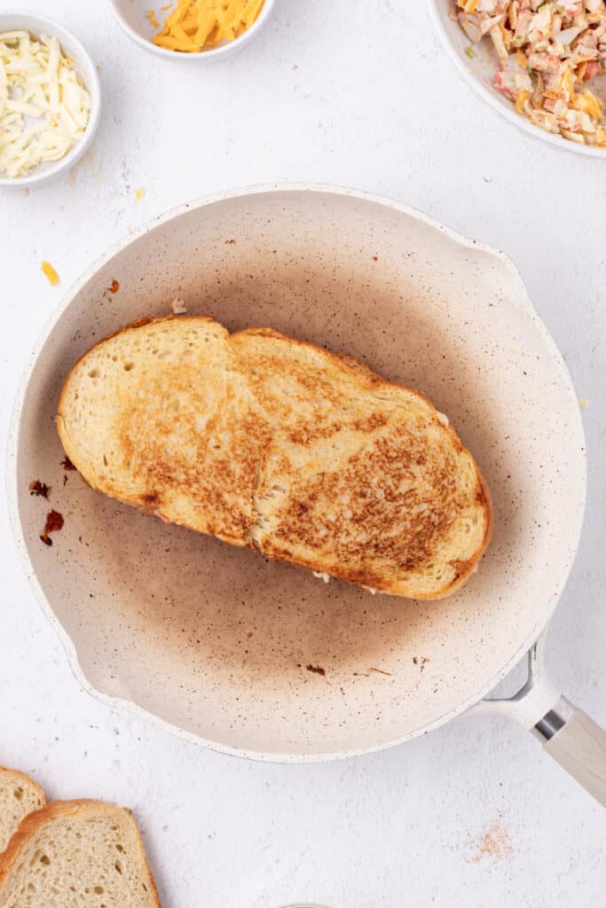 Cheesy Crab Melt sandwich cooking in a skillet until golden brown
