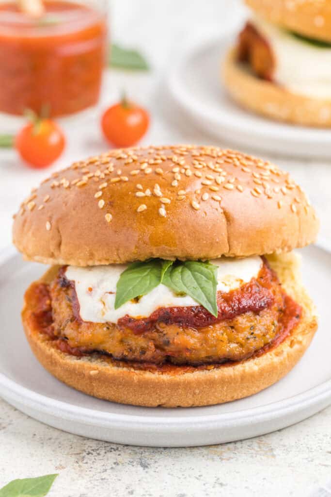 Chicken Parm Burger topped with marinara sauce, melted mozzarella, and basil on a sesame seed bun