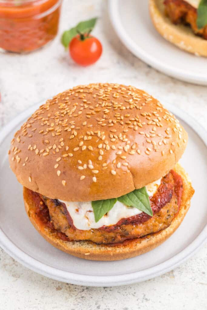 Chicken Parm Burger with marinara sauce, mozzarella cheese, and basil on a sesame seed bun