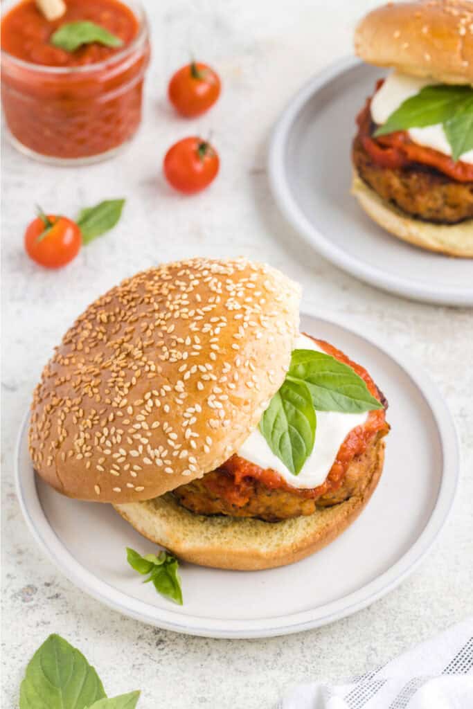 Chicken Parm Burger topped with mozzarella cheese and basil on a sesame seed bun