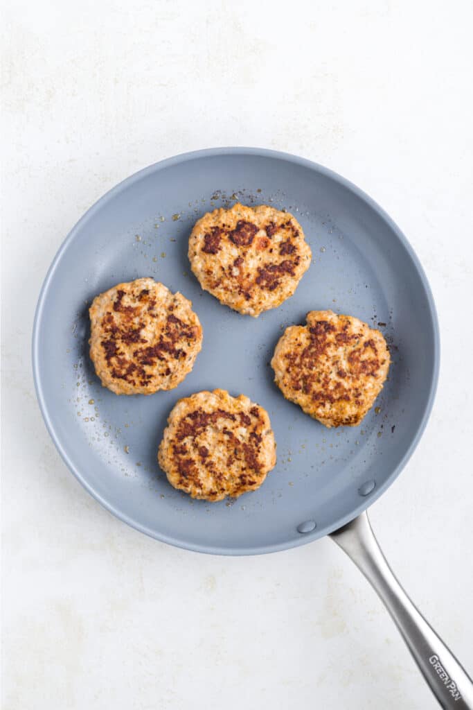 Chicken Parm Burger patties cooking in a skillet