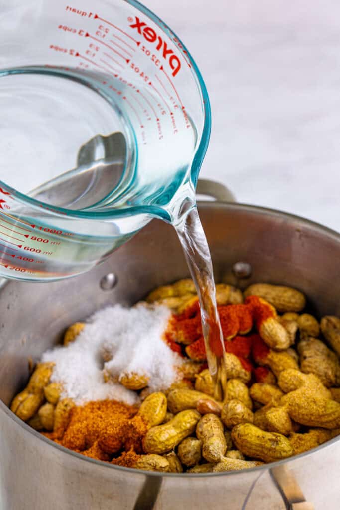 Water being poured over seasoned raw peanuts to make Creole Boiled Peanuts.