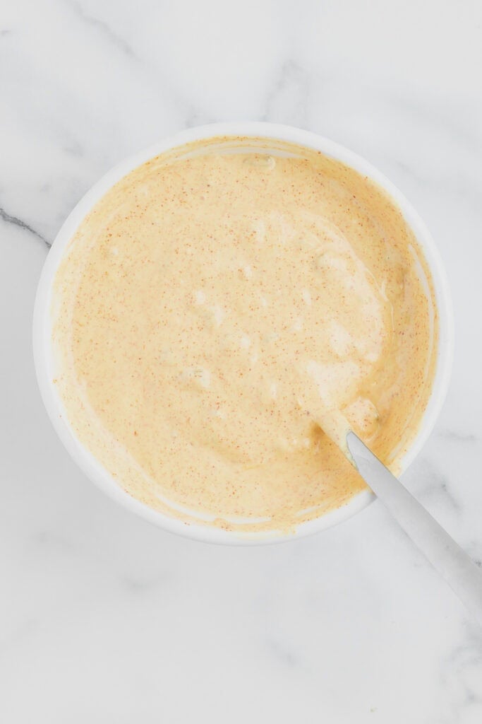 Homemade burger sauce mixed together in a white bowl with a spoon resting inside.