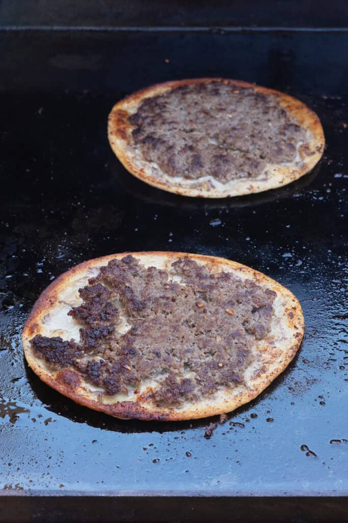 Smash Burger Tacos cooking on a griddle with browned beef and crispy tortillas.