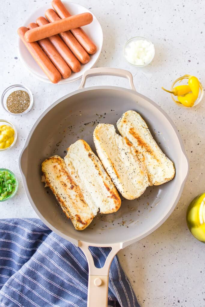 Toasting poppy seed hot dog buns in butter for homemade Chicago Hot Dogs
