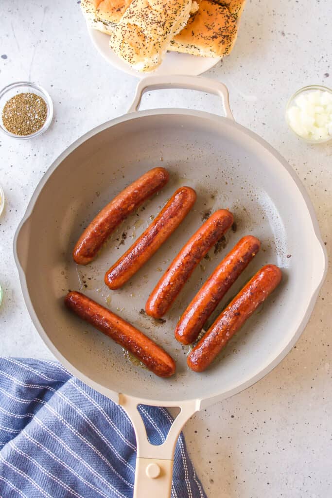 All-beef hot dogs browning in a skillet for Chicago Dogs