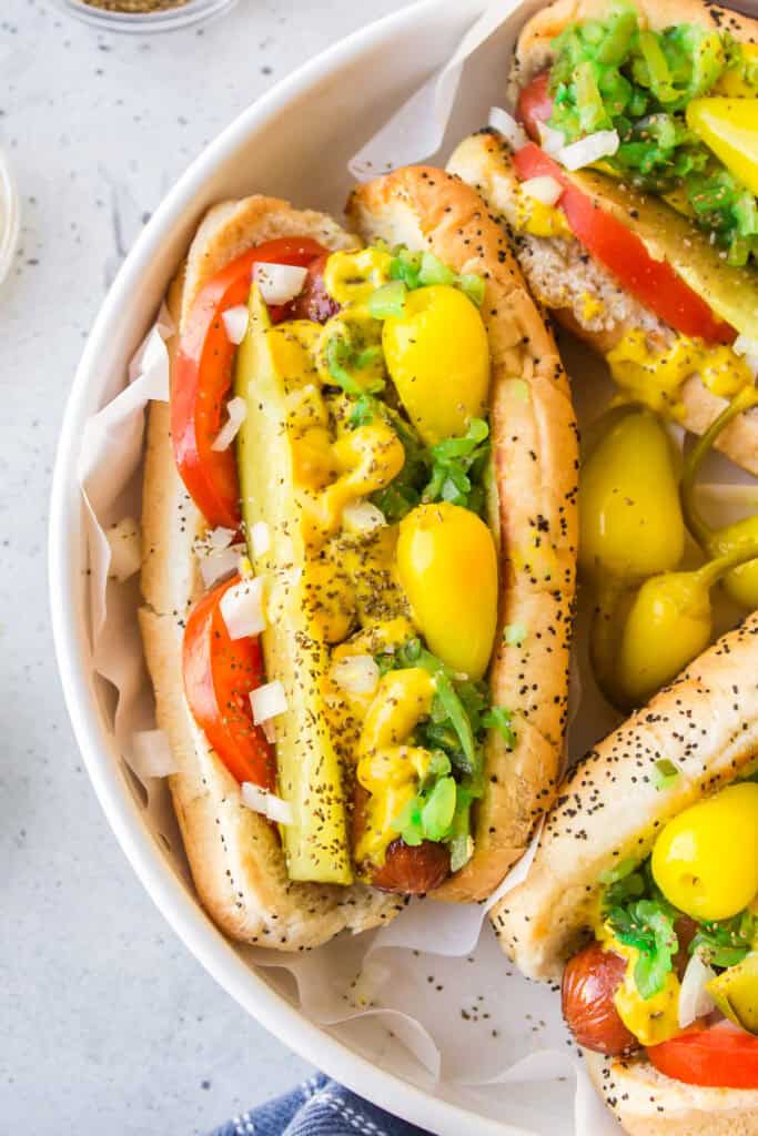 Close-up of an authentic Chicago Hot Dog loaded with pickle spear, tomato, onion, sport peppers, relish, mustard, and celery salt