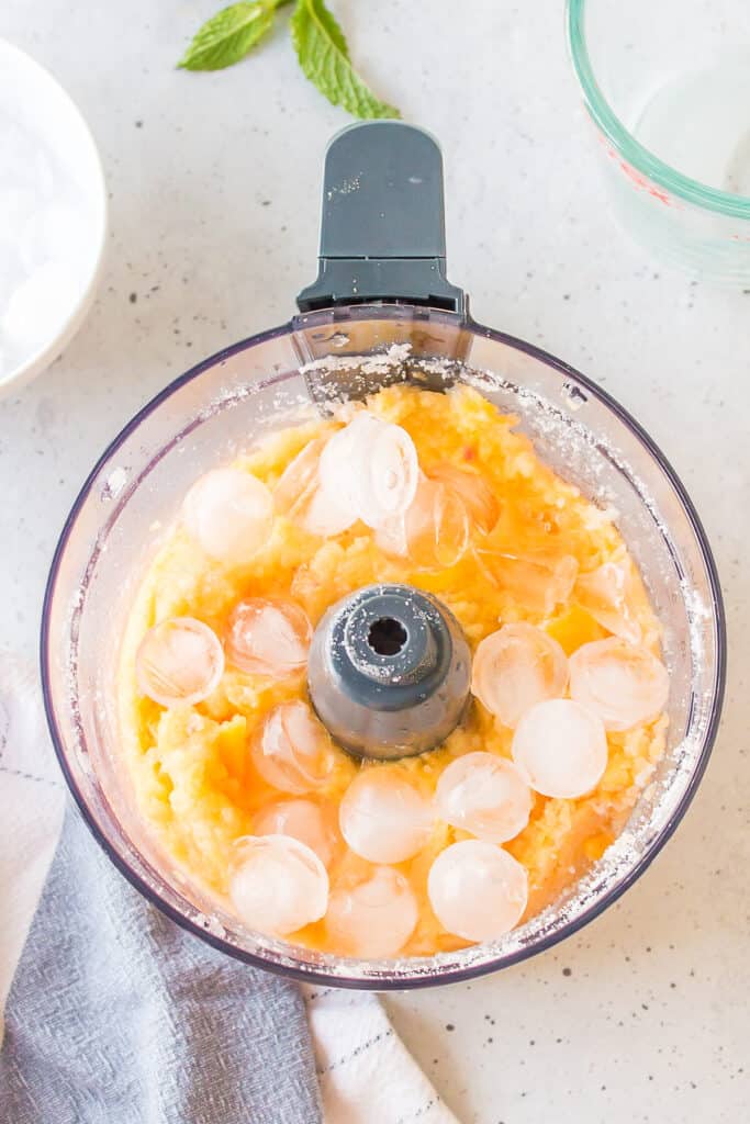 Frozen peaches mixed with ice before blending into a frozen peach cocktail.