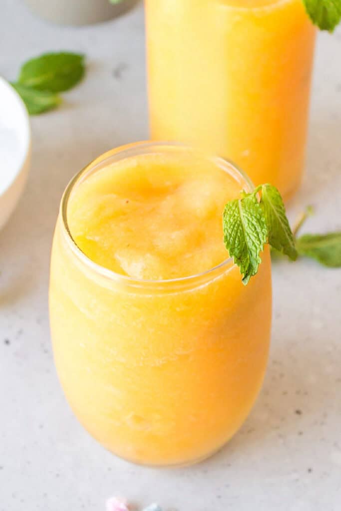 Refreshing frozen peach cocktail topped with fresh mint for a summer brunch drink.