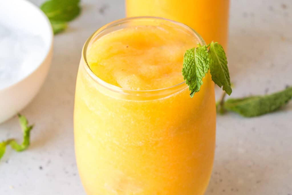 Frozen peach Prosecco cocktail served with fresh mint and a thick icy consistency.