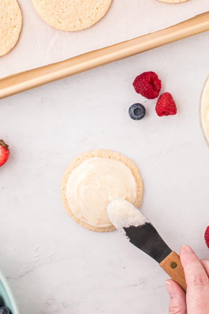 Cream cheese frosting spread over a cooled sugar cookie before decorating.