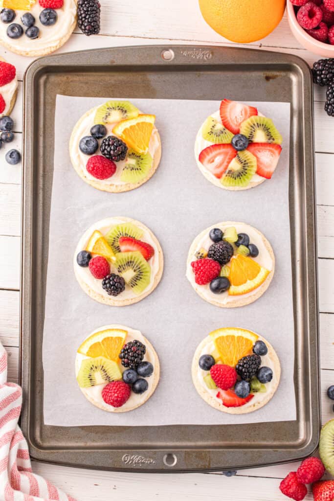 Fruit Pizza Cookies decorated with colorful fresh fruit on a baking sheet.