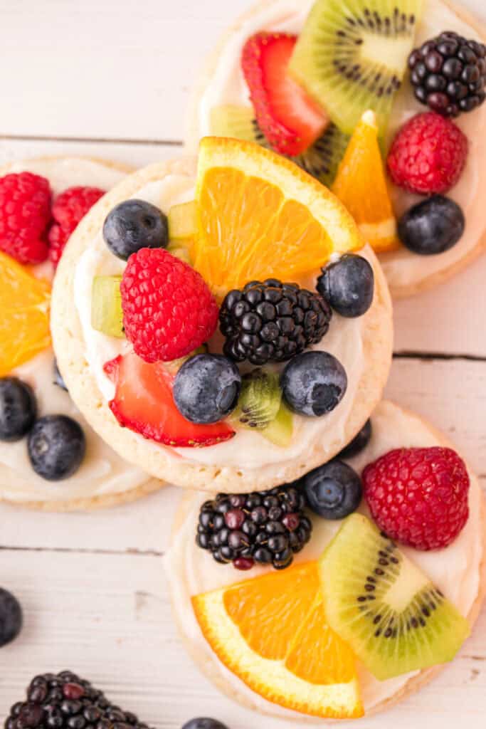 Close-up of a homemade Fruit Pizza Cookie topped with cream cheese frosting and fresh fruit.
