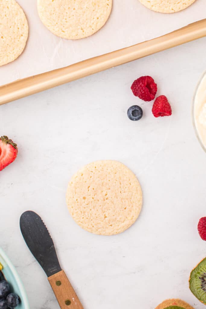 Baked sugar cookies cooling before decorating with frosting and fresh fruit.