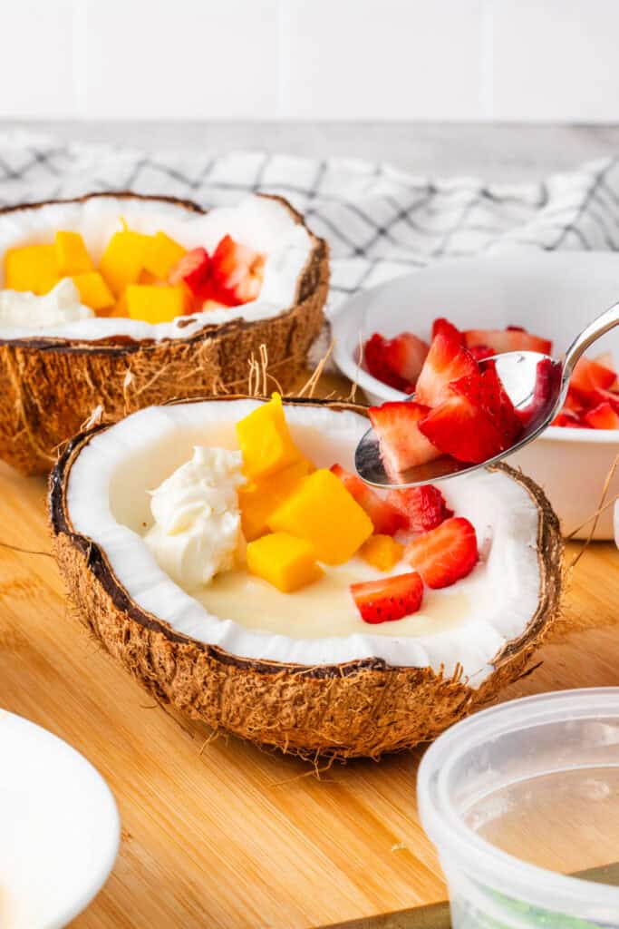 Fresh strawberries arranged around the shaved ice in a coconut shell.